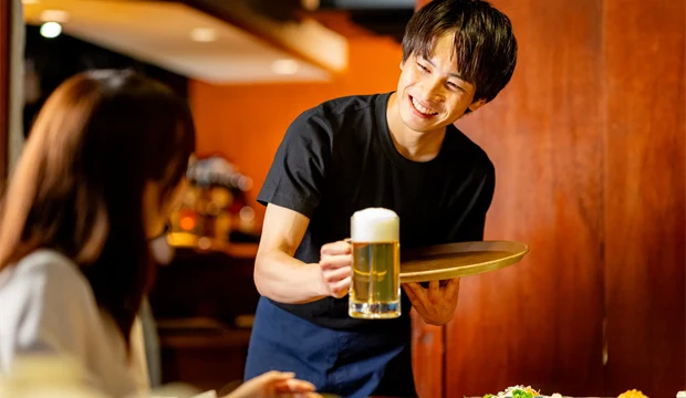 居酒屋でスタッフが料理と飲み物を運んでいる様子